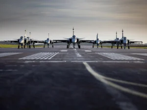 Шесть истребителей Gripen на взлётно-посадочной полосе под облачным небом
