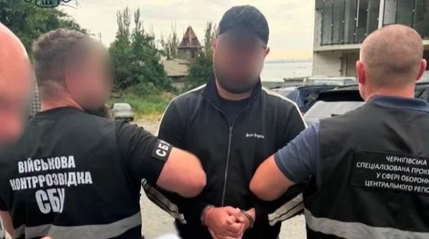 Затриманий чоловік у наручниках між співробітниками СБУ та прокуратури
