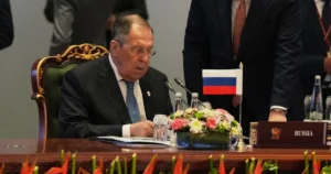 Сергій Лавров за столом переговорів з прапором Росії та табличкою Russia