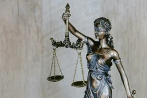Бронзовая статуя богини правосудия с весами и мечом на деревянном фоне