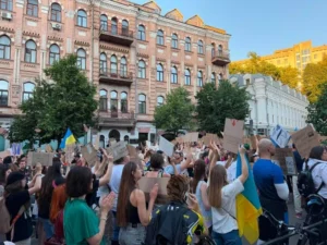 Толпа протестующих с украинскими флагами и плакатами возле исторических зданий Киева