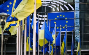 Флаги Украины и ЕС перед стеклянным зданием с эмблемой Евросоюза