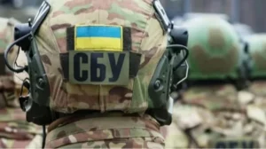 Спина военнослужащего в камуфляже с шевроном флага Украины и нашивкой СБУ