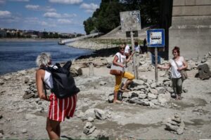 Люди йдуть по обмілілому кам’янистому дну Дунаю біля мосту