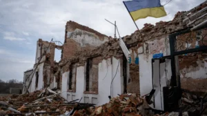 Зруйнована цегляна будівля з українським прапором серед купи уламків