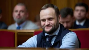 Олексій Кулеба усміхається в залі парламенту на червоному кріслі