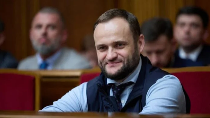 Олексій Кулеба усміхається в залі парламенту на червоному кріслі