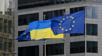 Прапори України та ЄС майорять перед скляним фасадом сучасної будівлі
