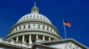 Купол Капітолію США з американським прапором під чистим блакитним небом