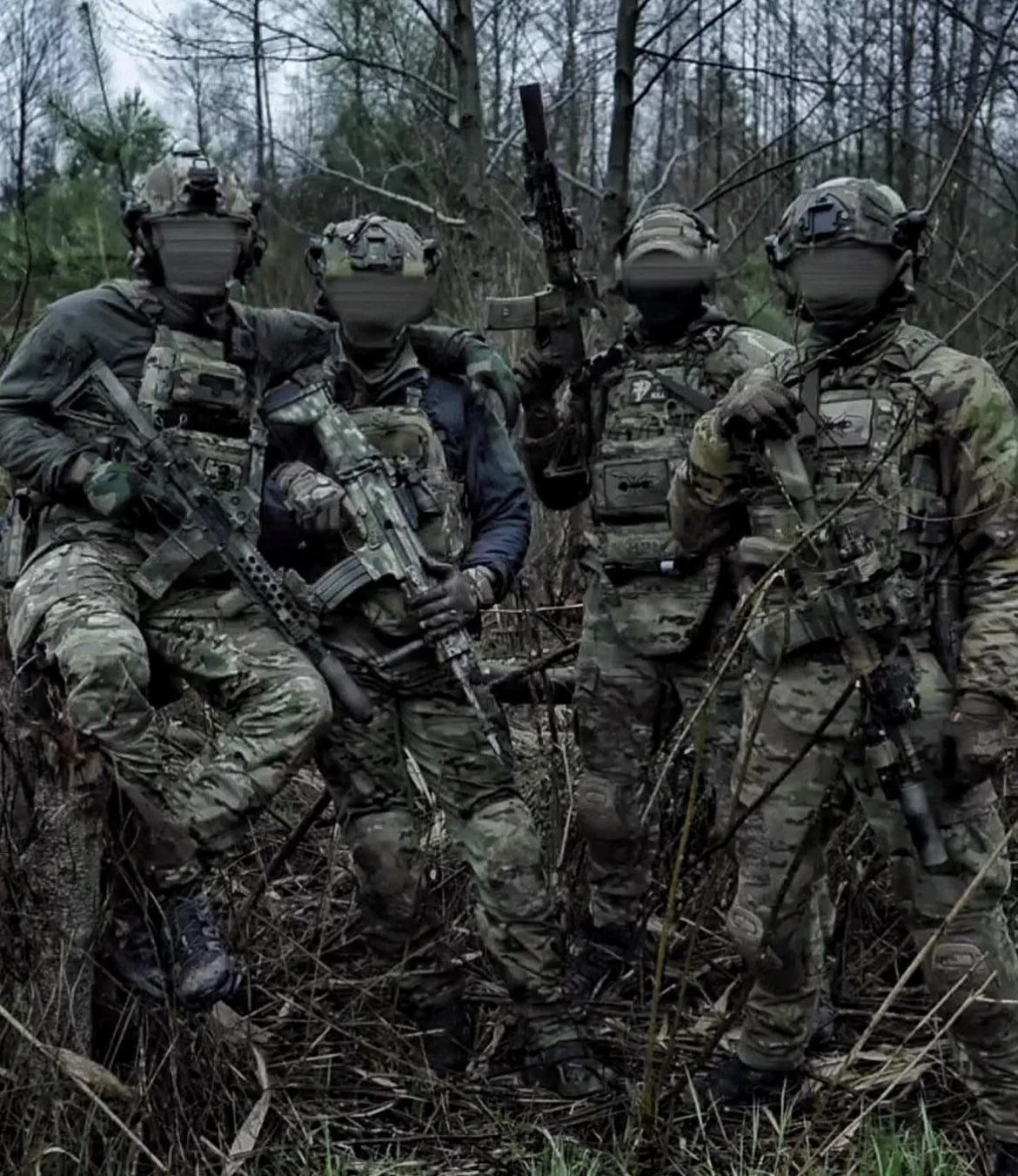 Чотири бійці ССО в камуфляжі зі зброєю стоять у лісі