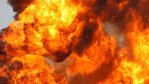 Яскрава помаранчево-жовта пожежа з густим чорним димом на тлі світлого неба