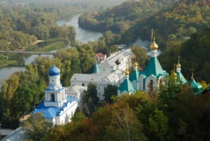 Православный монастырь с голубыми куполами среди осеннего леса